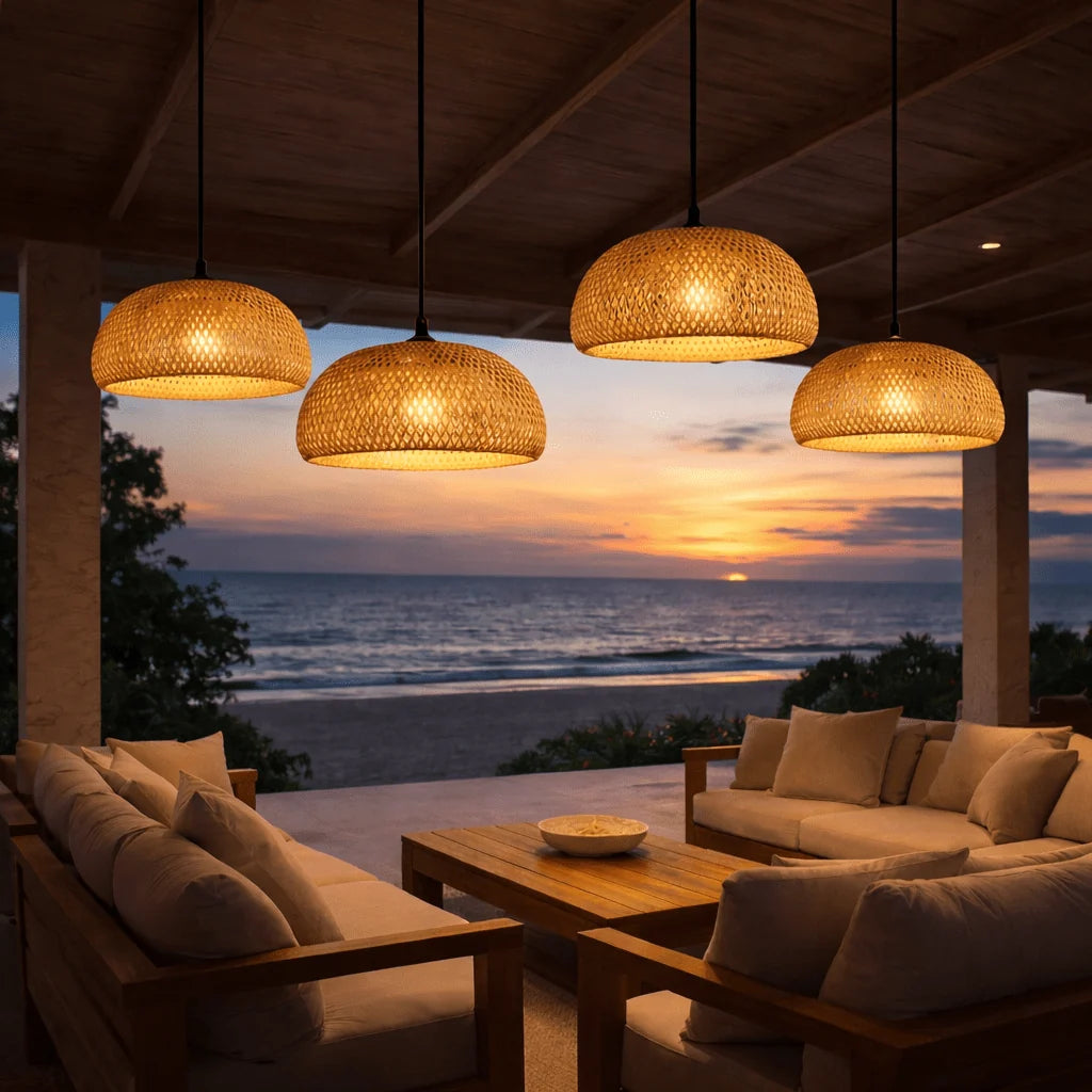 Four woven bamboo pendants lit over an outdoor terrace at sunset